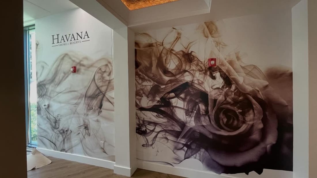 Business interior with a full smoke-and-rose wall mural wrap behind a branded logo